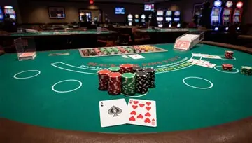 Table de blackjack avec des jetons empilés et un as et un 10 visibles