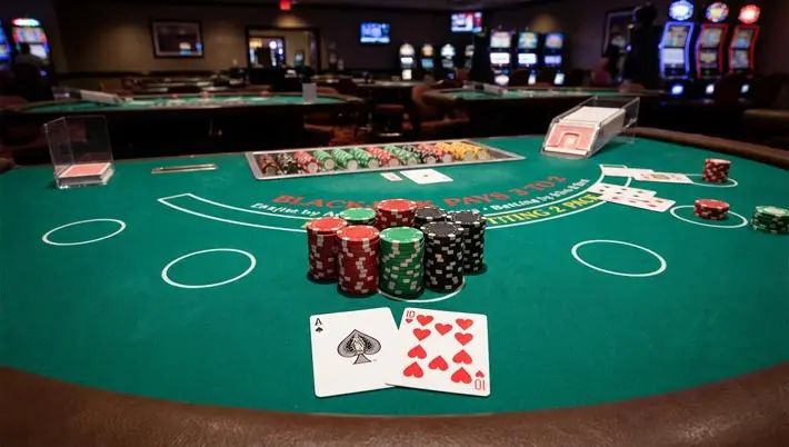 Table de blackjack avec des jetons empilés et un as et un 10 visibles